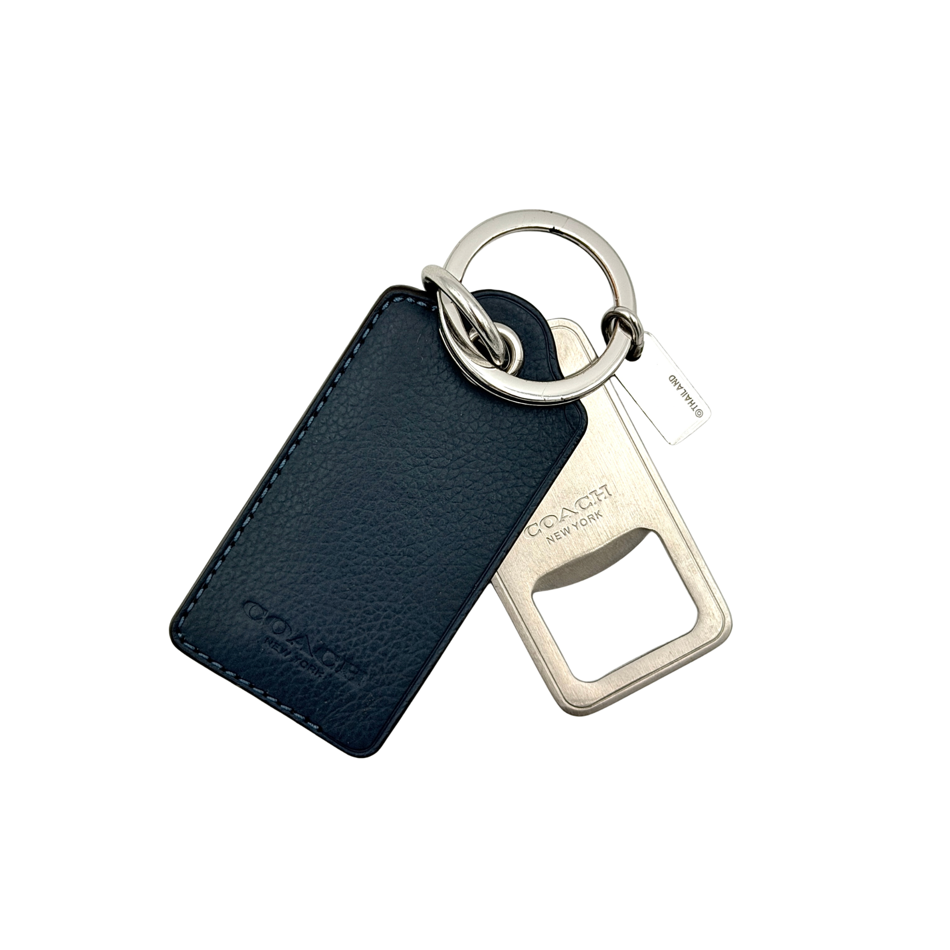 Coach bottle opener key fob in navy blue pebbled leather and silver-tone hardware, featuring a Coach New York embossed tag and integrated opener.