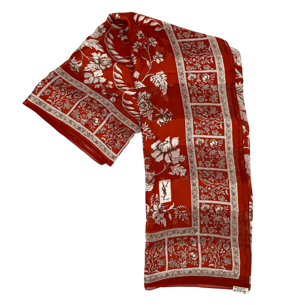 Saint Laurent silk scarf in rich red, featuring intricate cream floral designs and ornate borders with the YSL monogram visibly displayed.