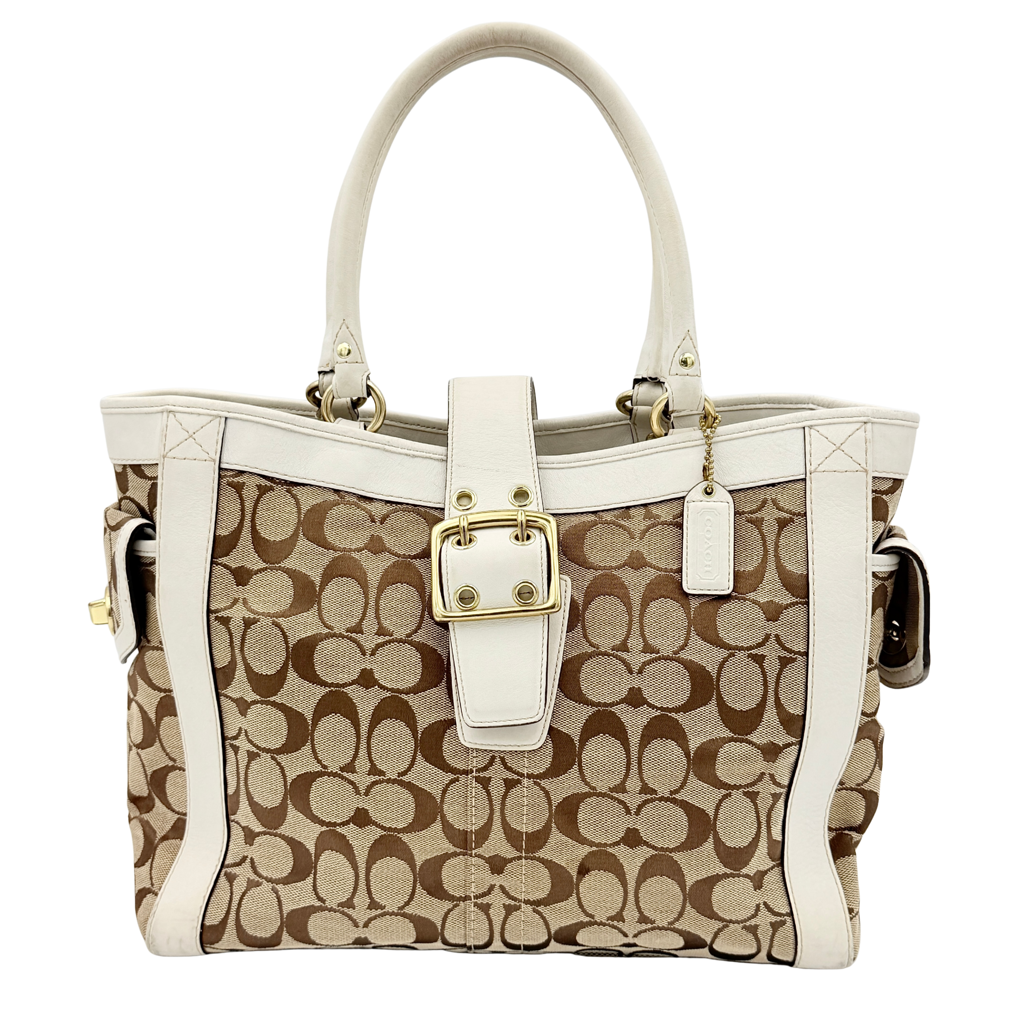 Coach Signature Soho Buckle Tote in beige canvas with white leather trim and gold-tone hardware, displayed against a clean background.