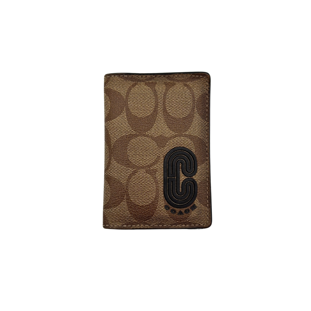 Coach Signature Canvas Patch Card Wallet in beige canvas with bold black logo patch, displayed closed against a white background.