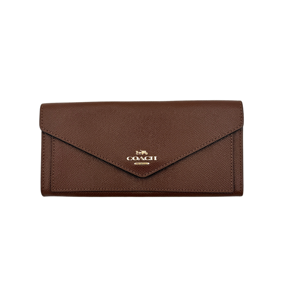 Coach brown envelope long wallet in textured leather with gold hardware, shown closed with the signature horse and carriage logo.