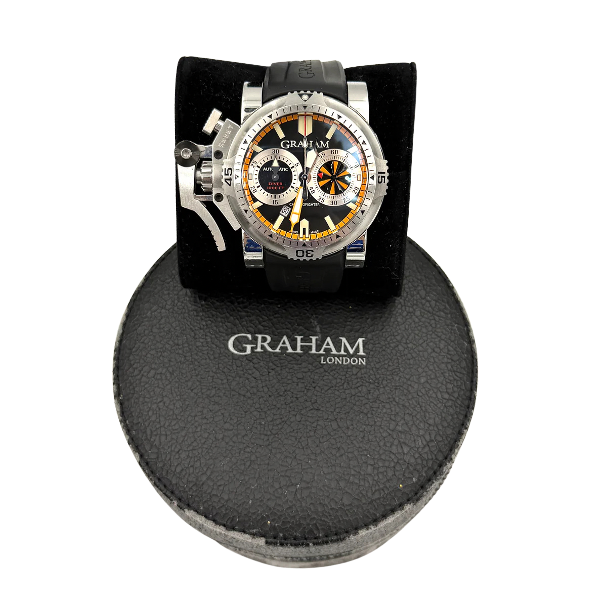 The Graham Chronofighter Oversize Diver 2OVES.B15A watch displayed in its signature round Graham London presentation case, showcasing its bold black dial, prominent chronograph trigger, and black rubber strap.