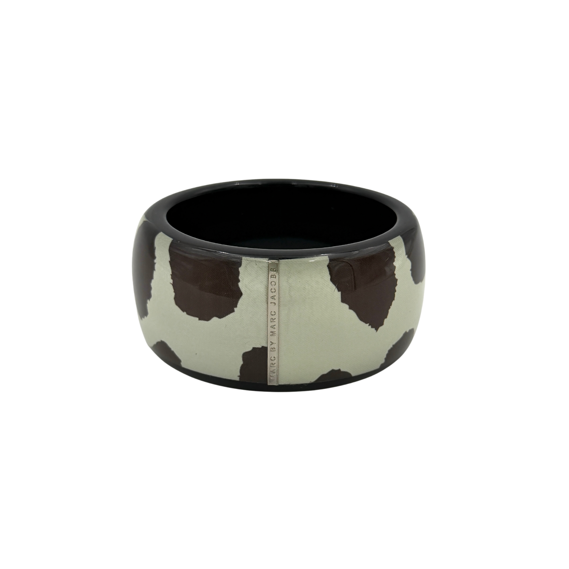 A wide Marc Jacobs bangle bracelet in sage green and dark brown cow print resin, featuring a slim silvertone logo plaque.