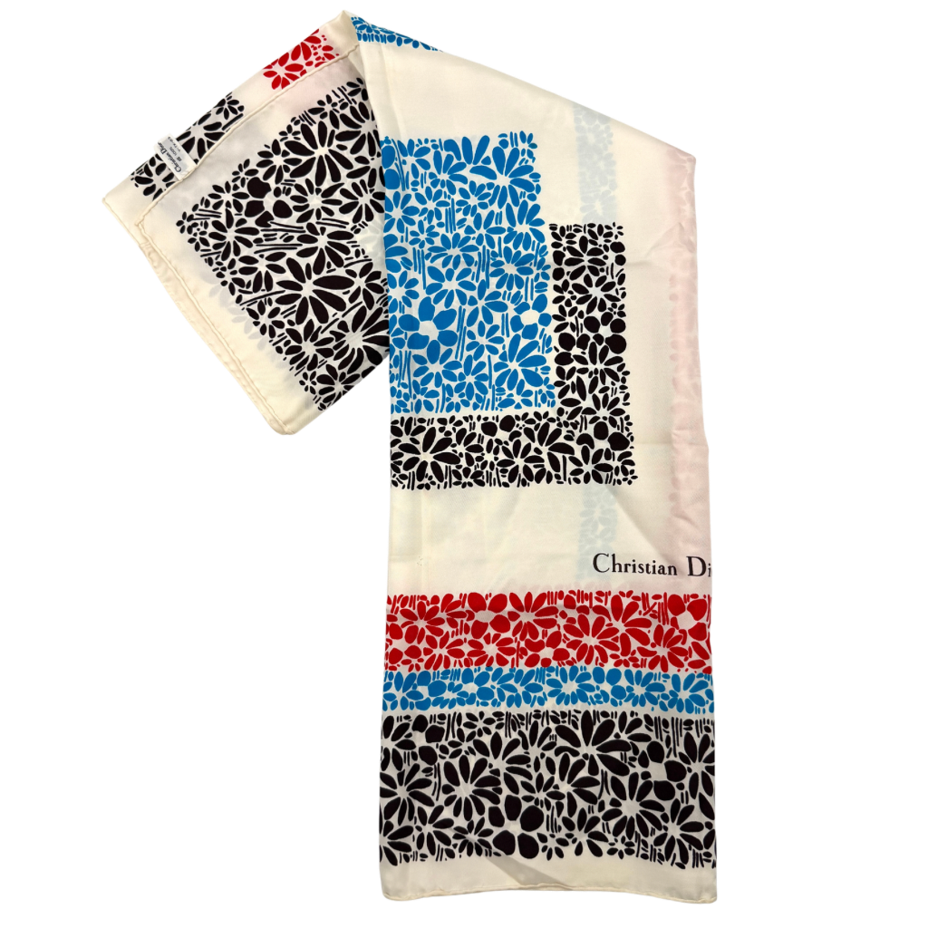 Dior silk scarf featuring a bold multicolor geometric floral pattern in red, blue, black, and ivory with the Christian Dior logo visible at the corner.