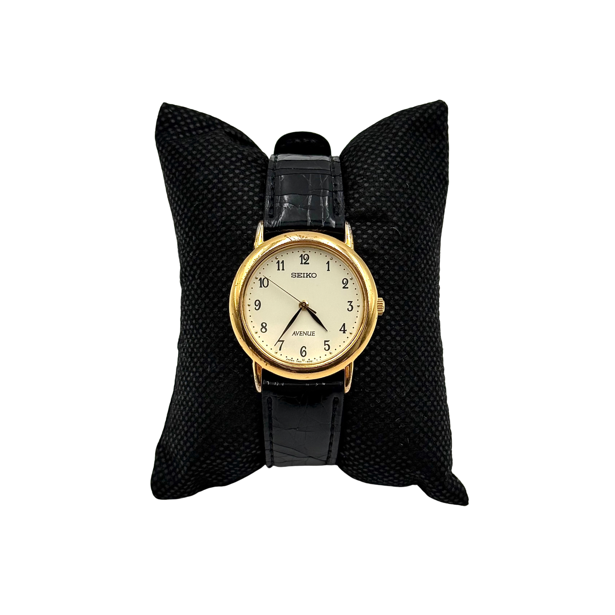 Seiko Avenue 7N01-6D50 gold watch with black textured leather strap displayed on a black cushion.