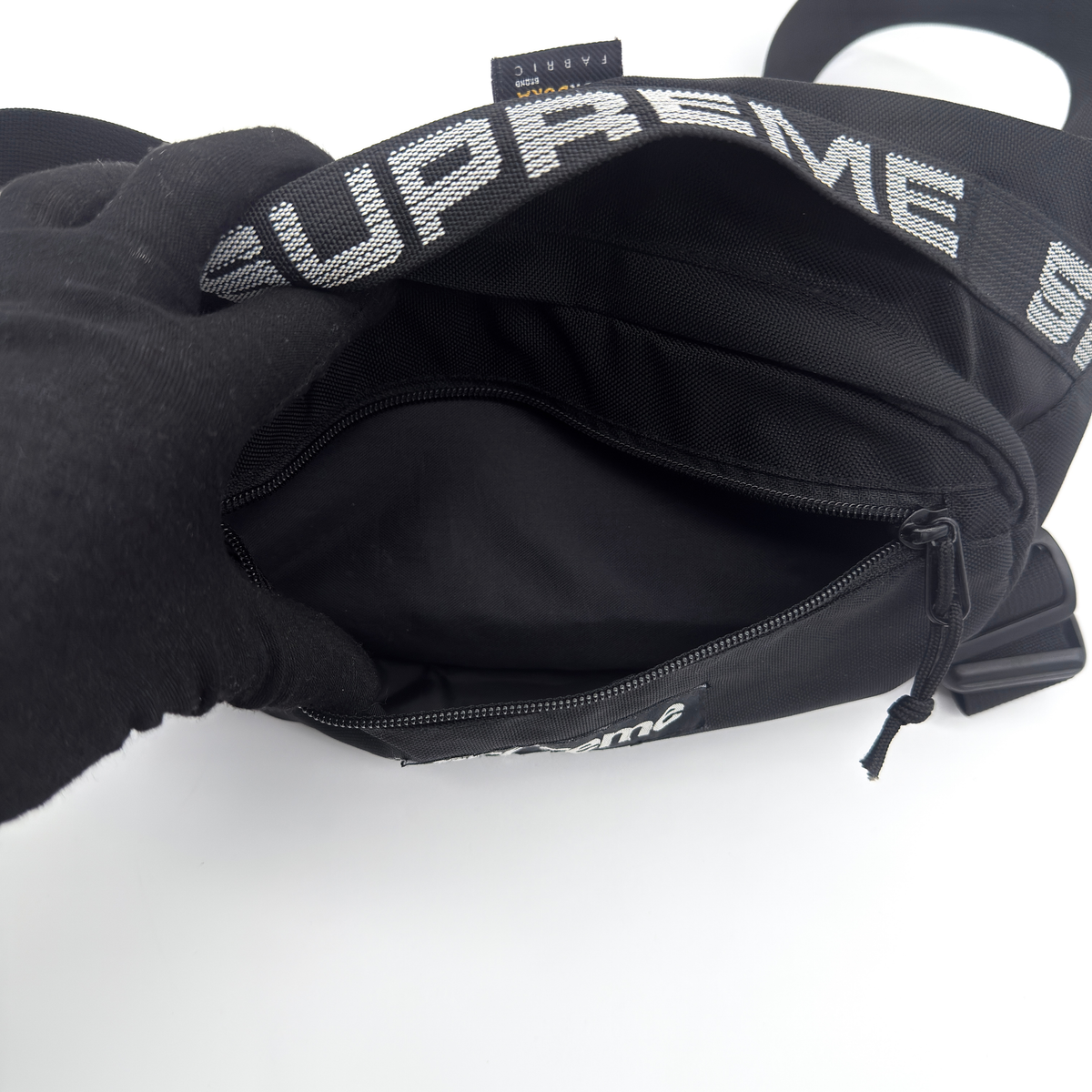 Supreme Box Logo Waist Bag in black Cordura fabric with white logo and logo-woven adjustable strap, laid flat to show its front design.