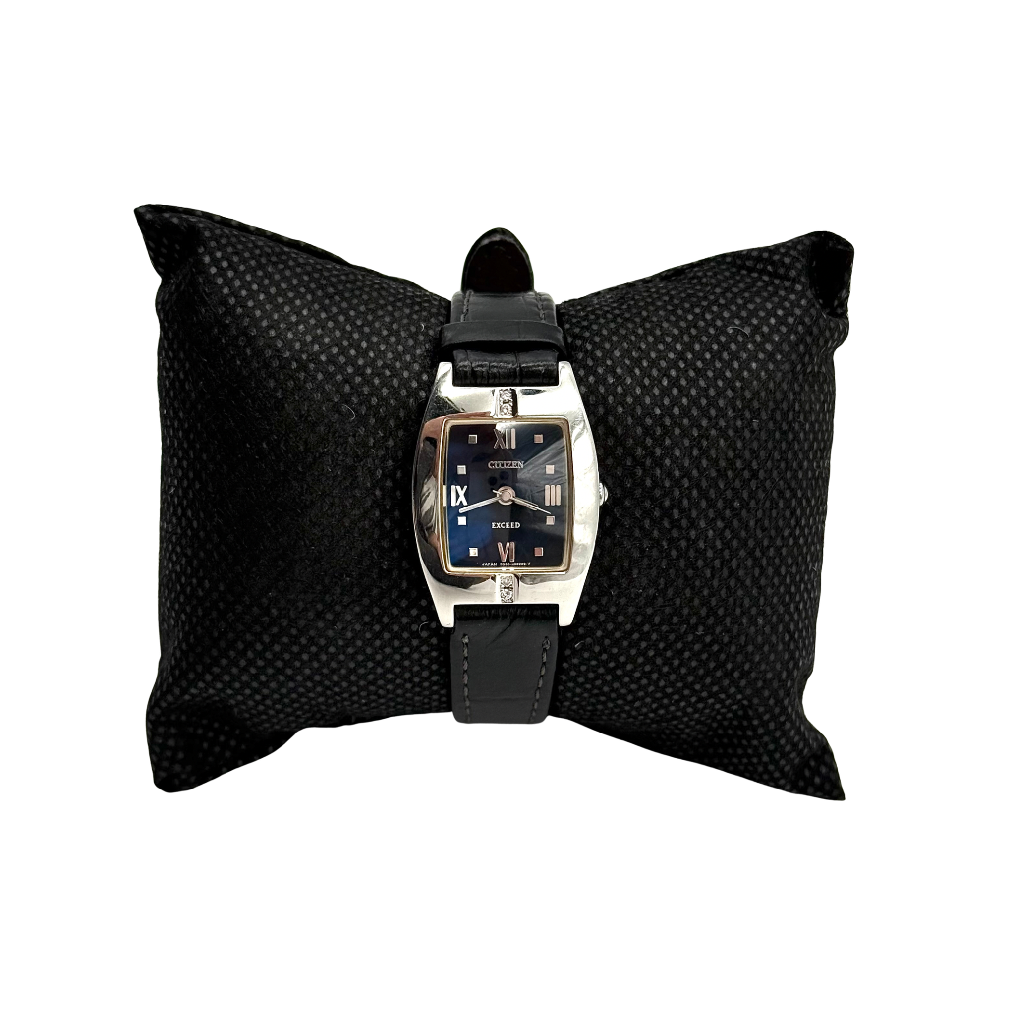 Citizen Exceed watch featuring a dark blue dial, tonneau-shaped stainless steel case, and black leather strap displayed on a black cushion.