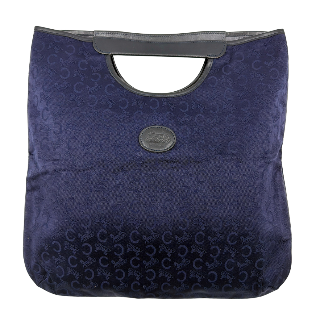 Celine Noevir Macadam Foldover Tote in navy jacquard with carriage motif, leather trim and cutout handles, photographed against a white background.
