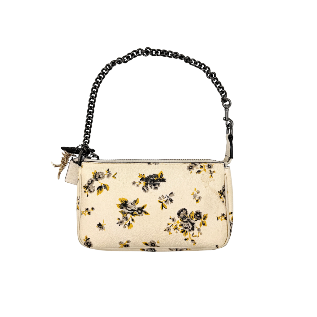Coach Nolita 19 shoulder bag in white pebbled leather with yellow and grey floral print, chunky gunmetal chain strap, and decorative charms.