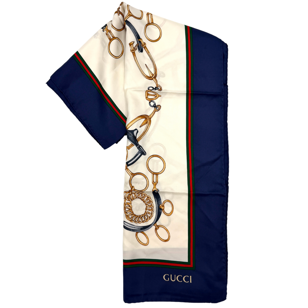 Gucci silk scarf with equestrian horsebit print, navy borders, and large GG logo displayed against a white background.