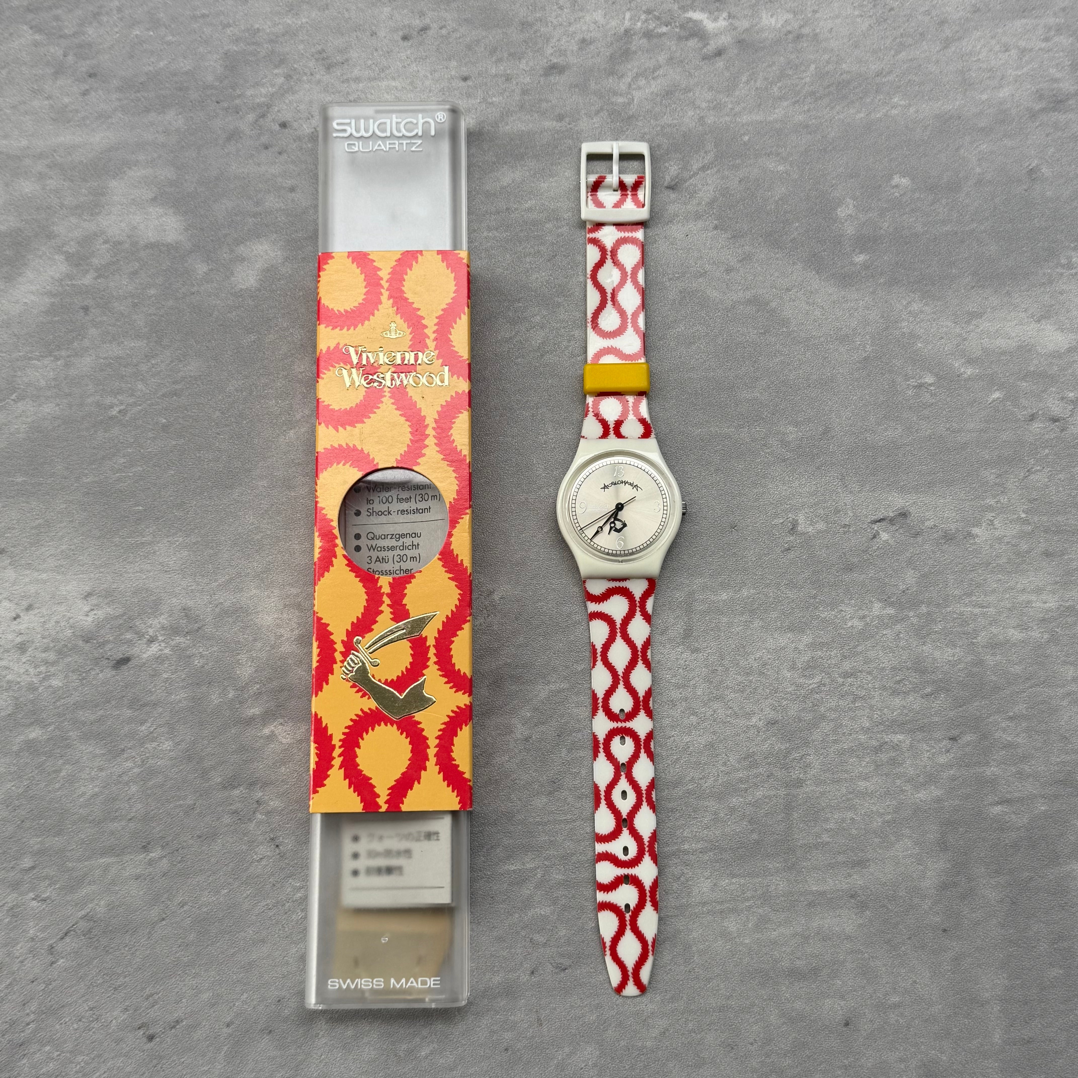 Vivienne Westwood x Swatch Anglomania watch with red and white patterned strap, yellow keeper, silver-tone dial, and original Swatch box.