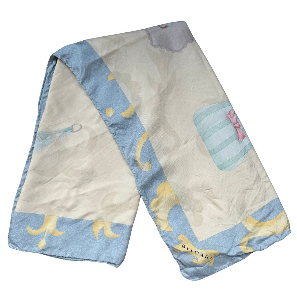 Bvlgari silk scarf in light blue and cream featuring a soft graphic print with border detailing and a smooth drape, shown folded and laid flat.