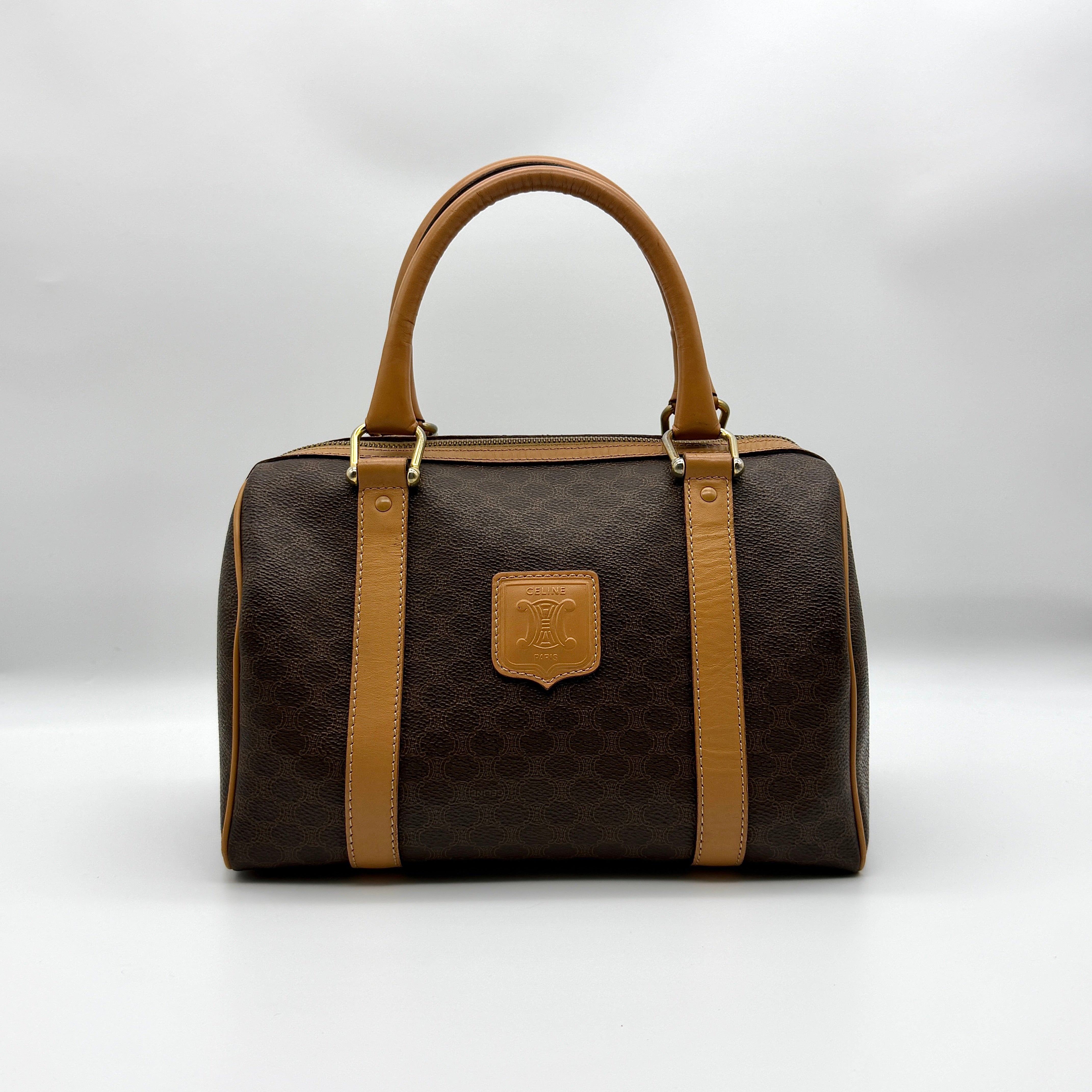 Celine Macadam Boston Bag Brown/Beige, crafted from coated canvas with tan leather trims and gold-tone hardware, featuring top handles and a zip closure.