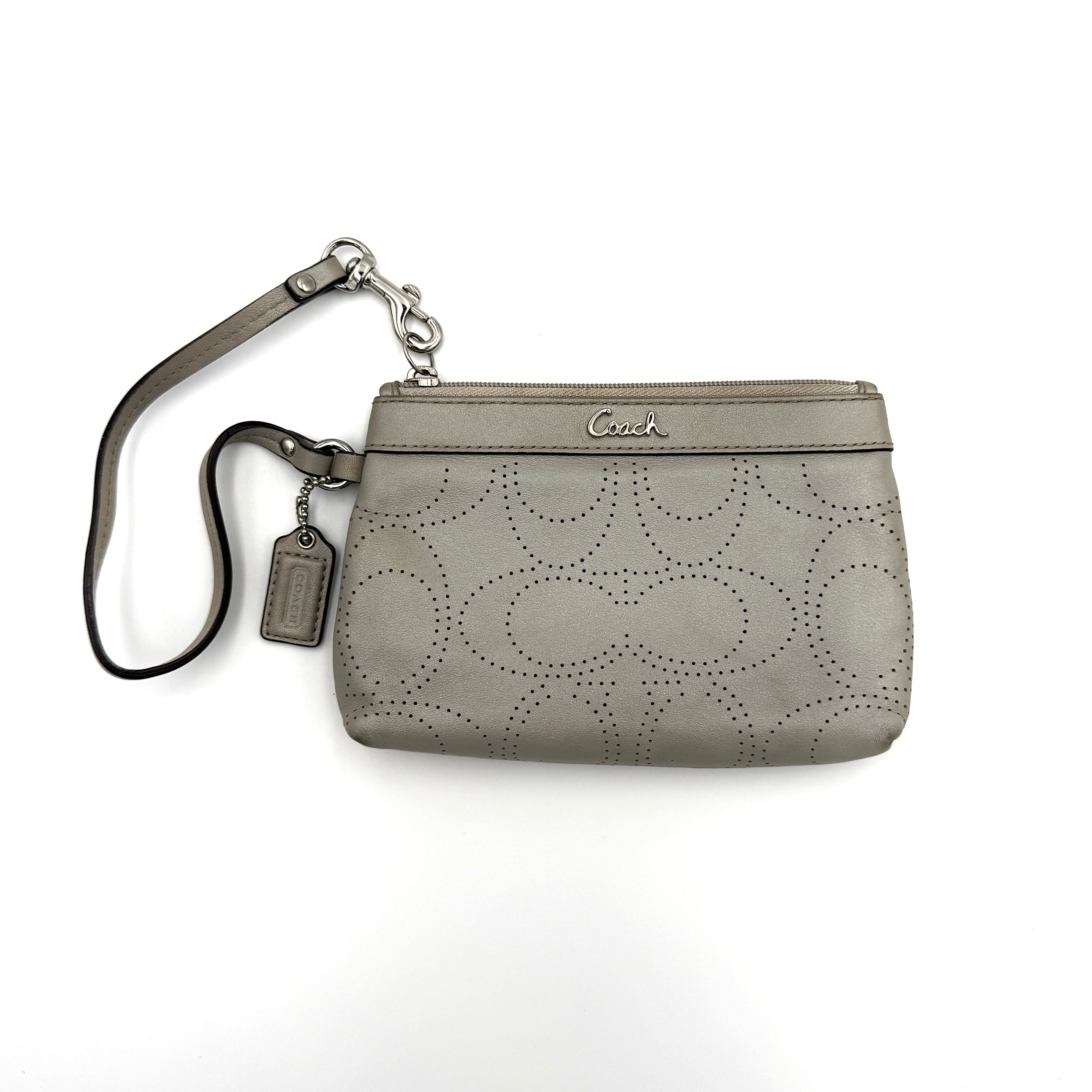 Coach wristlet in grey featuring perforated C design, compact and elegant for versatile use.