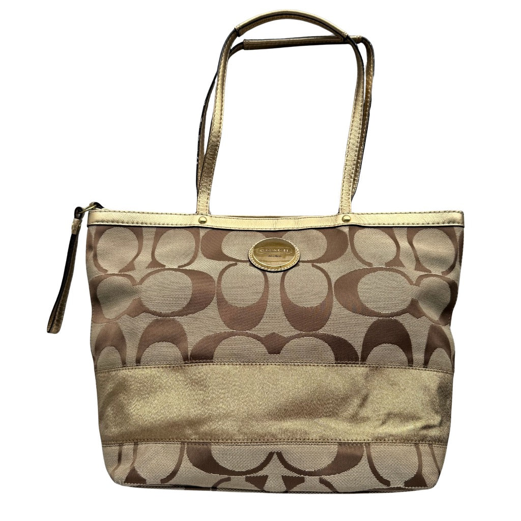 Coach signature stripe tote bag in beige featuring signature canvas, metallic gold stripe panel, gold-tone hardware, double shoulder straps, and top zip closure.