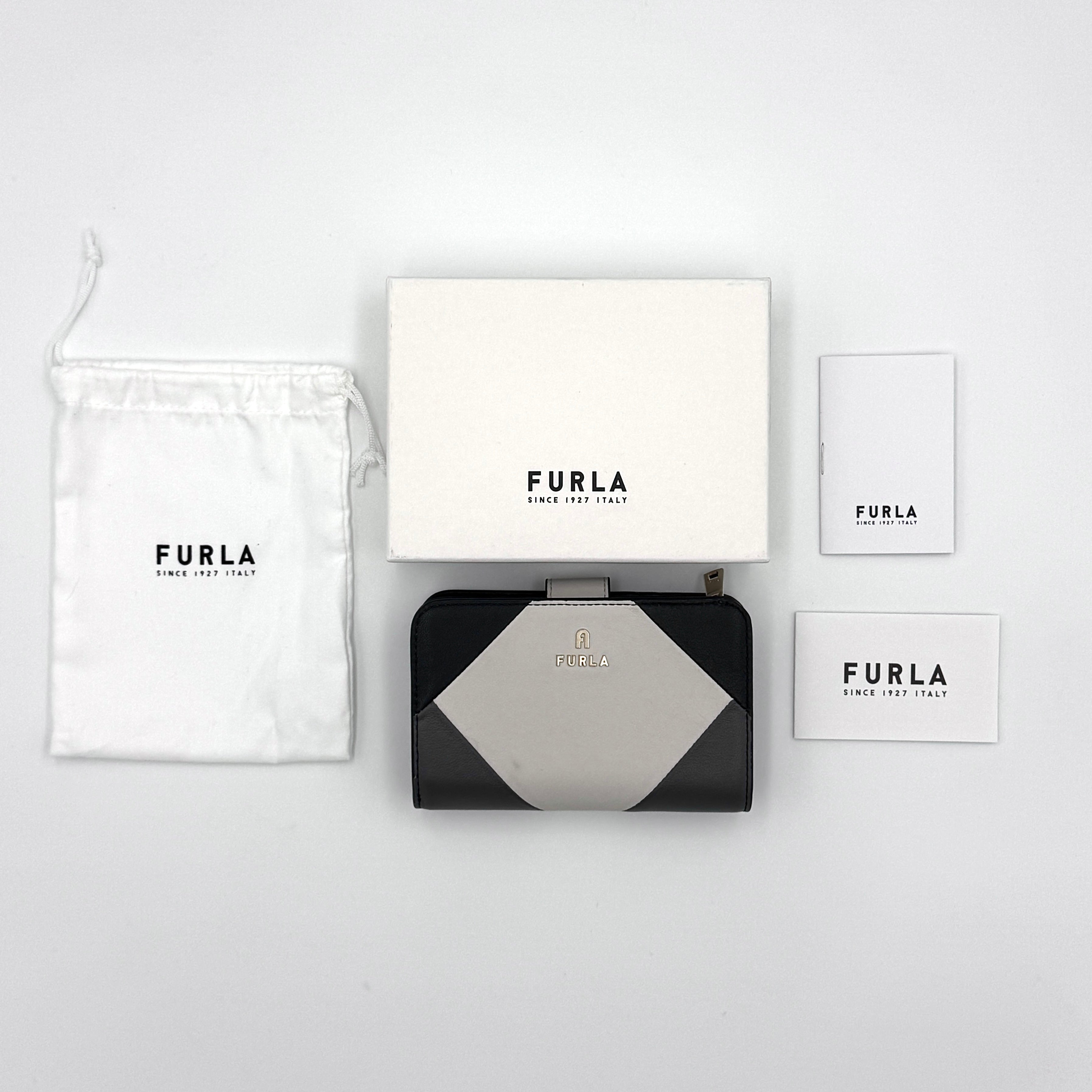 Furla Camelia M Compact Wallet in black and white, featuring a bi-color design with multiple interior compartments for card organization.
