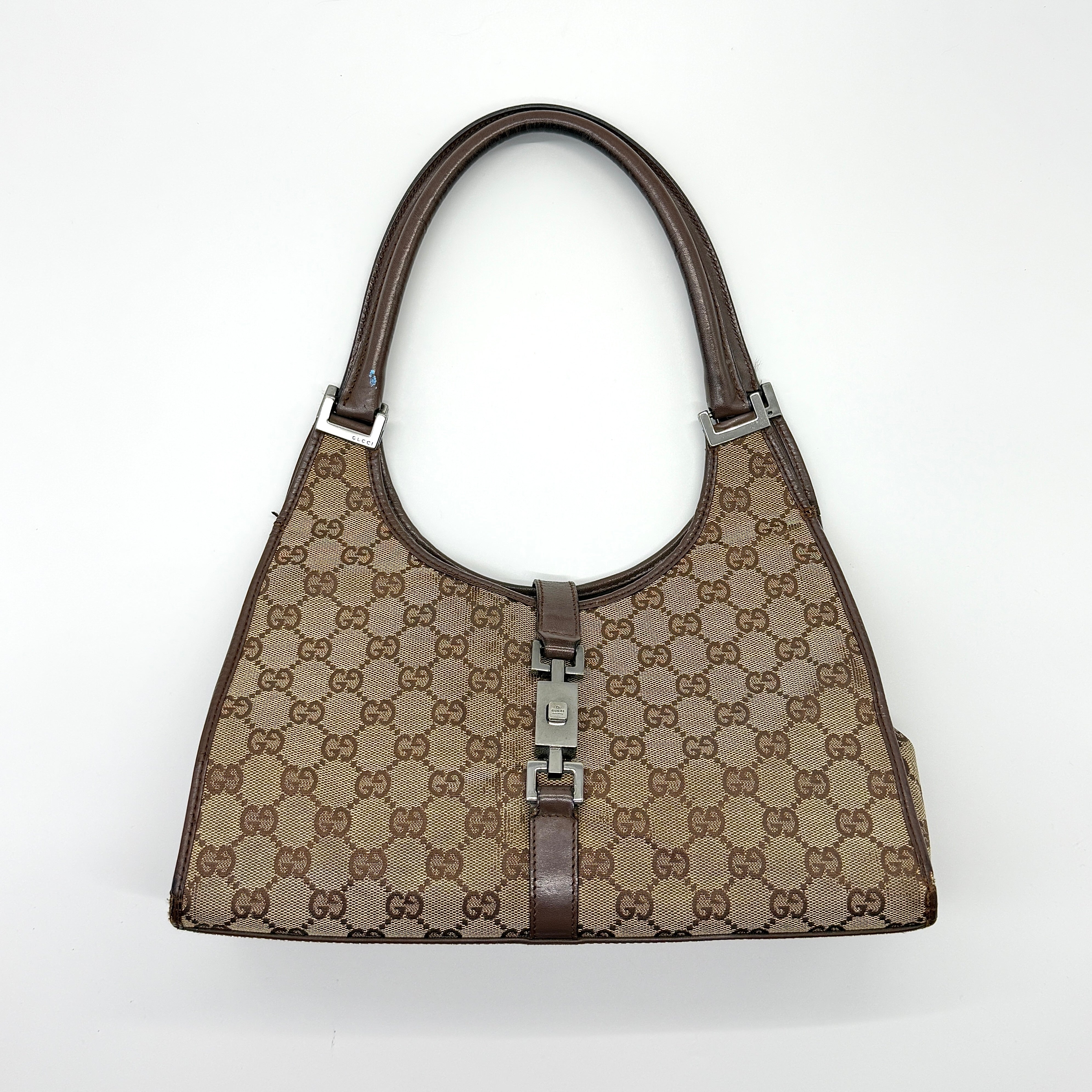 Gucci GG Monogram Jackie Shoulder Bag in beige/brown canvas with brown leather trim and silver-tone piston buckle.