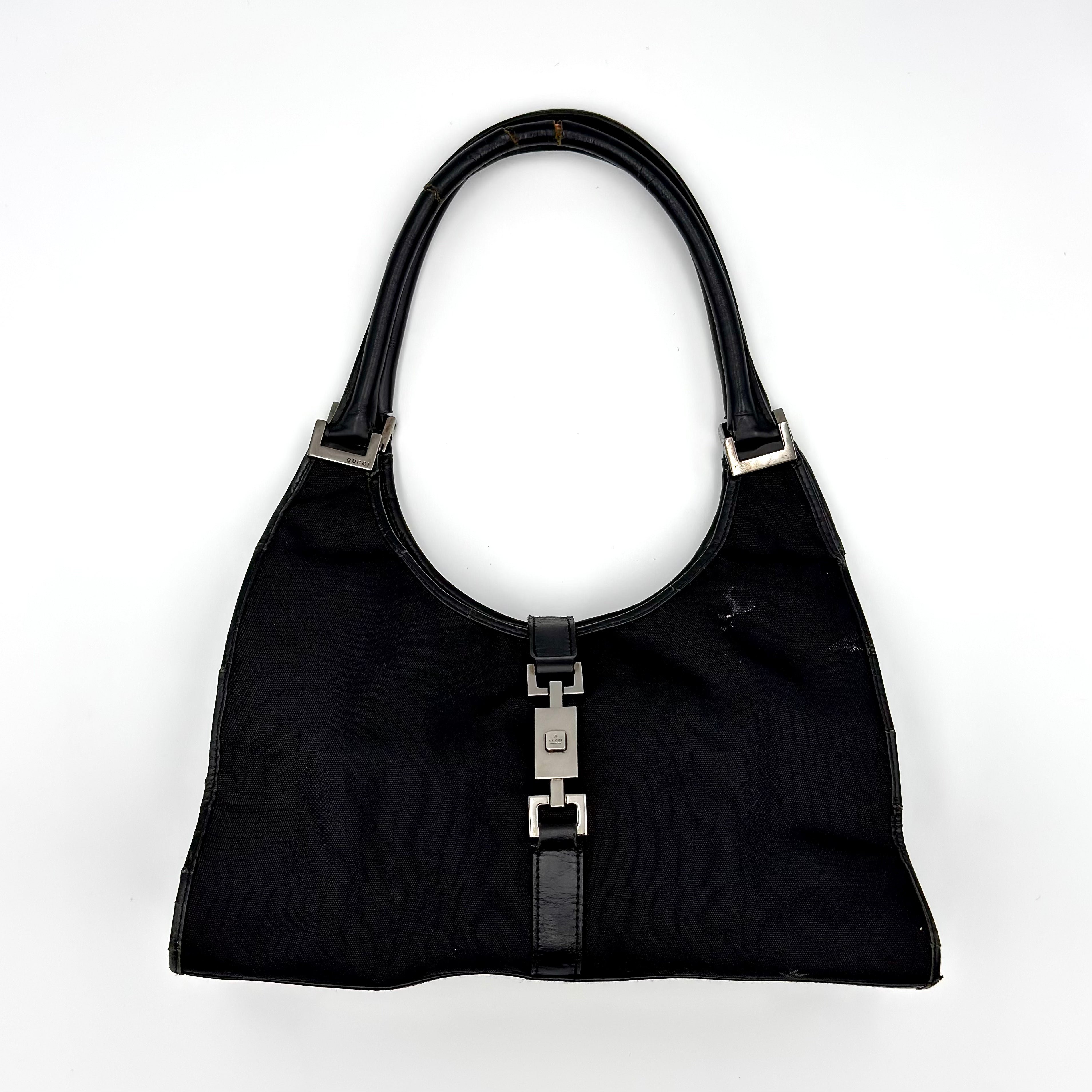 Gucci Jackie Bardot Hobo Shoulder Bag in black canvas with leather trim, silver-tone piston lock, and curved silhouette.