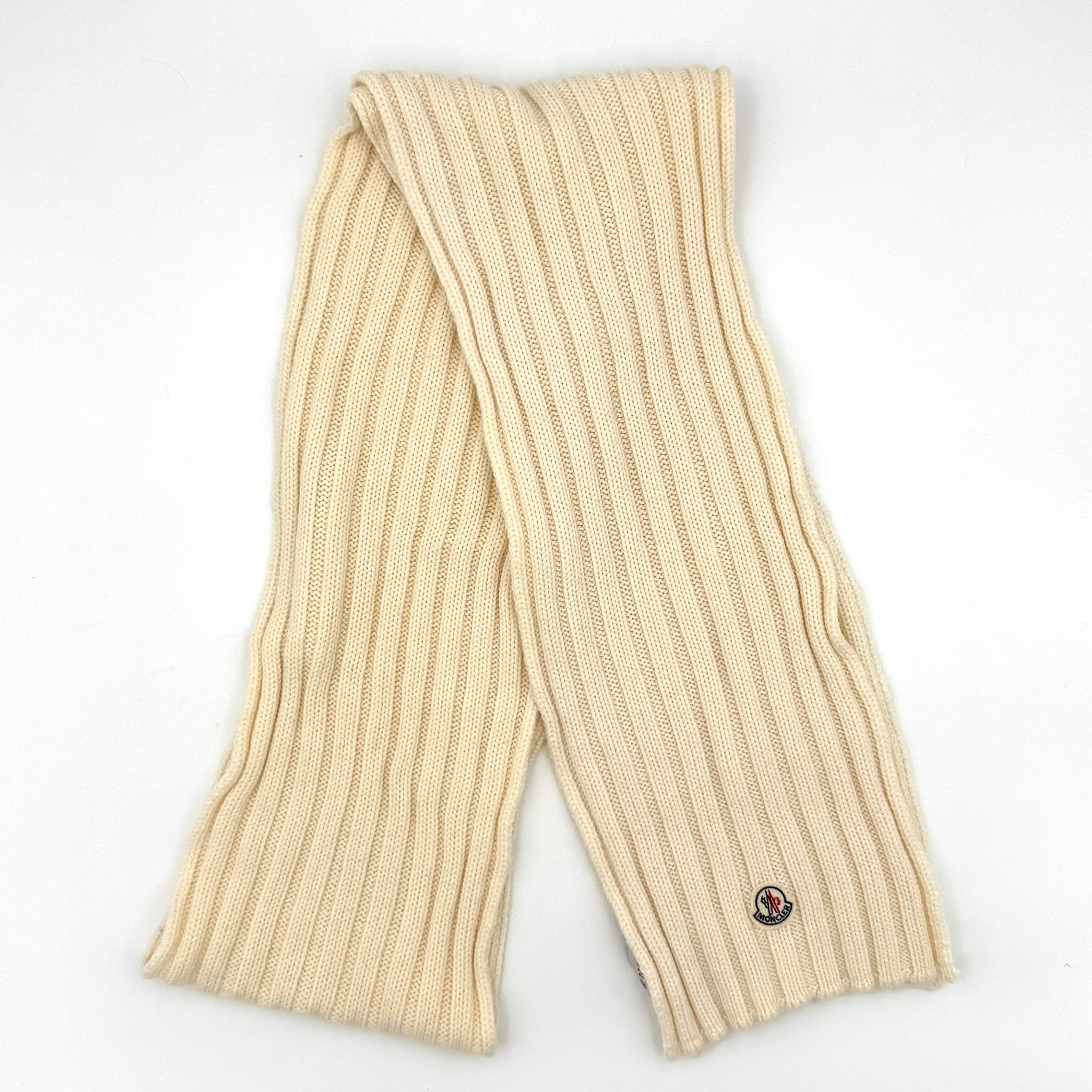 Moncler wool ribbed scarf in cream featuring a soft knit texture and signature logo patch.
