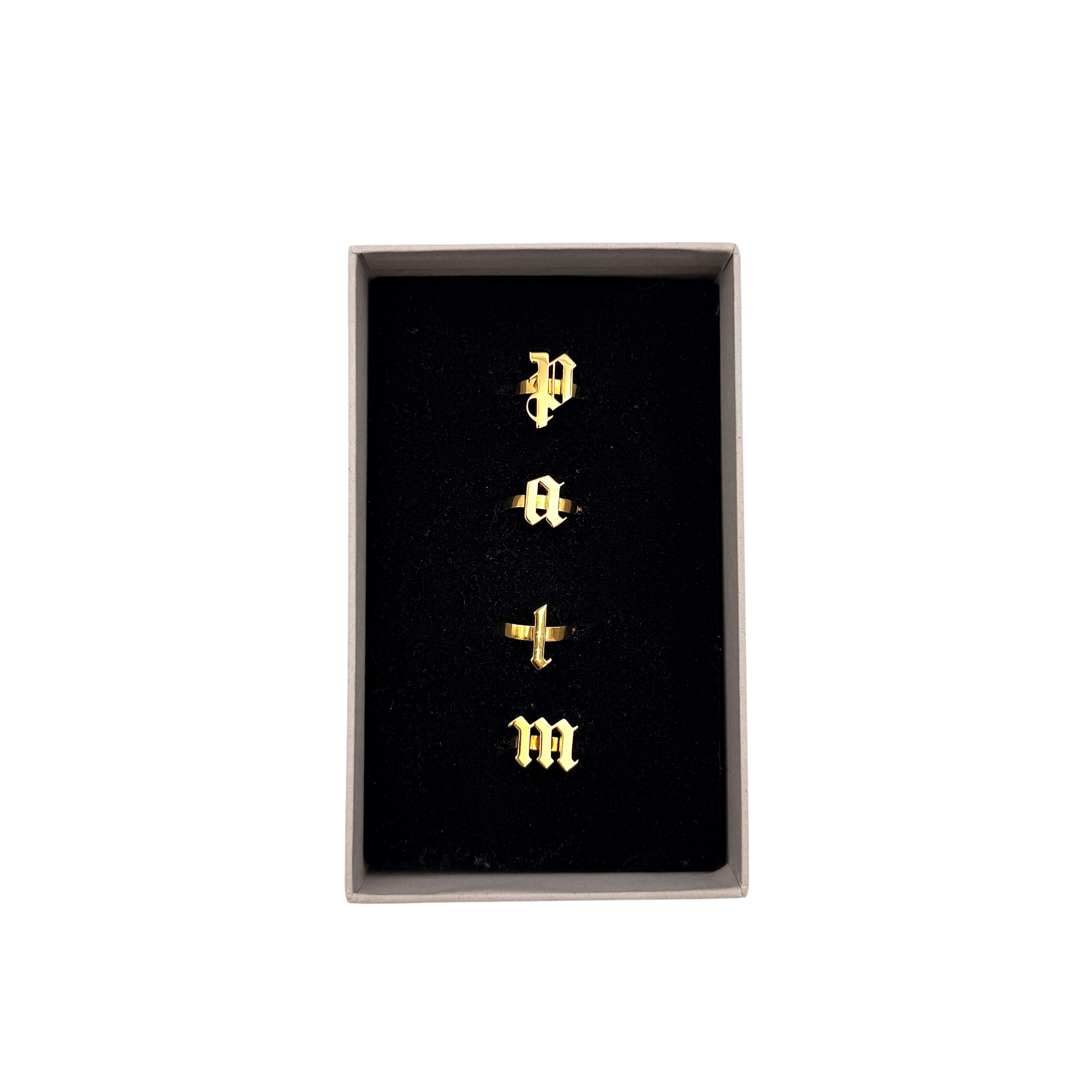 Palm Angels gold-tone rings set with letter-style design, shown with original box and packaging.
