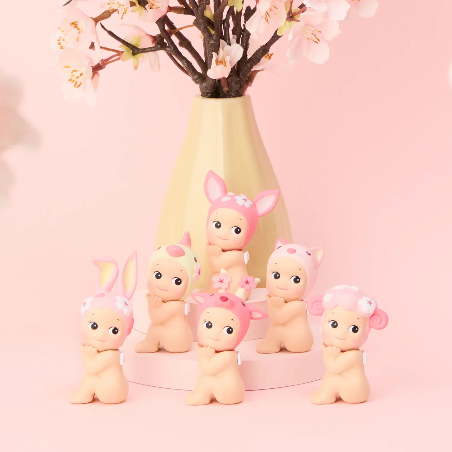Sonny Angel Cherry Blossom Series figures displayed in front of sakura backdrop with bunny and bear designs.